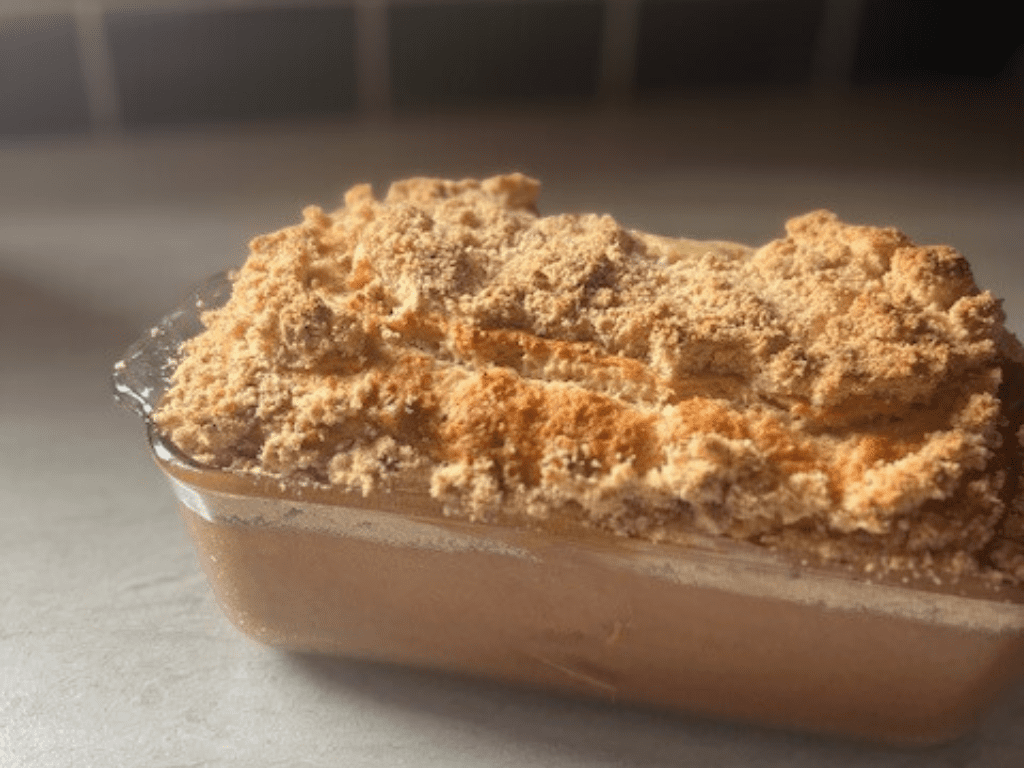 Moist banana bread with crumb topping in a glass loaf pan