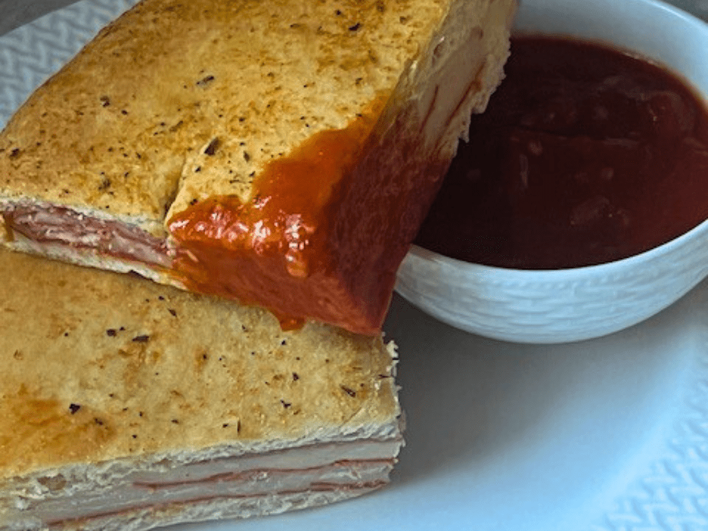 Homemade stromboli with pepperoni, salami, ham, cheese, and banana peppers sliced and ready to serve.