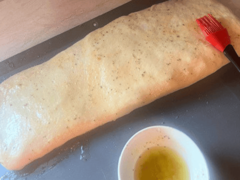 Rolled stromboli brushed with garlic butter and fresh basil before rising