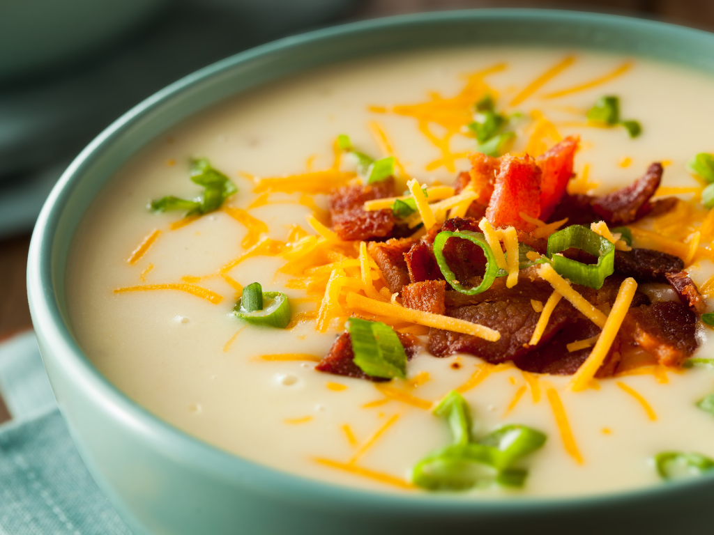 Creamy cheesy bacon potato soup topped with shredded cheese and crispy bacon