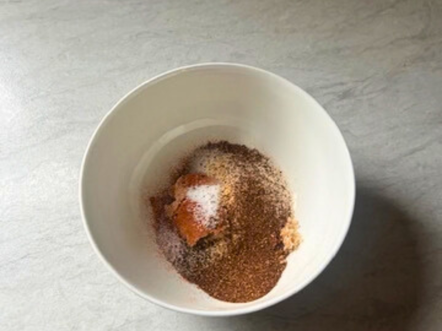 Slow cooker pulled pork dry rub seasoning in a white bowl on a kitchen counter