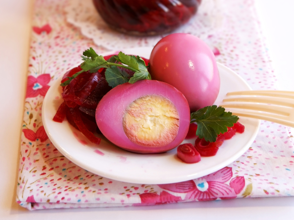 Purple pickled eggs on a dish with some sliced beets
