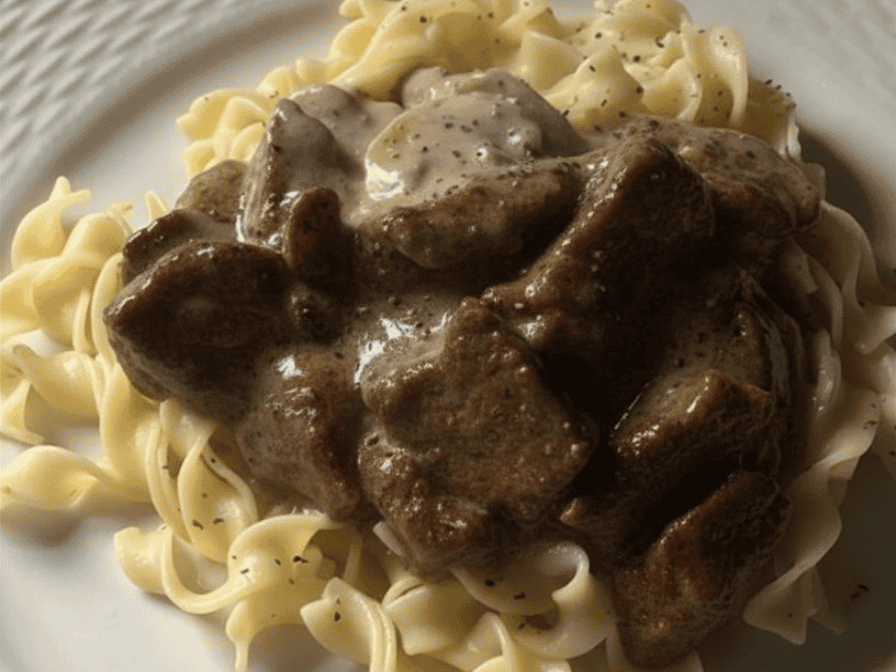 Slow cooker beef cubes in creamy mushroom gravy served over noodles