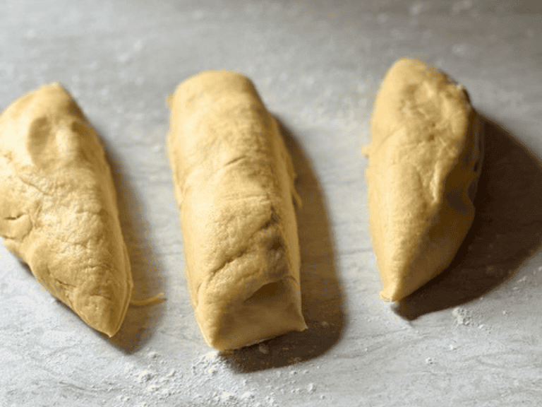 Hefekranz dough divided into three equal pieces on a floured surface