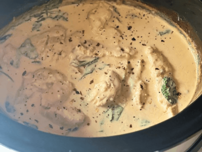 Creamy Italian chicken cooking in a slow cooker with a rich Parmesan cream sauce surrounding tender chicken breasts.