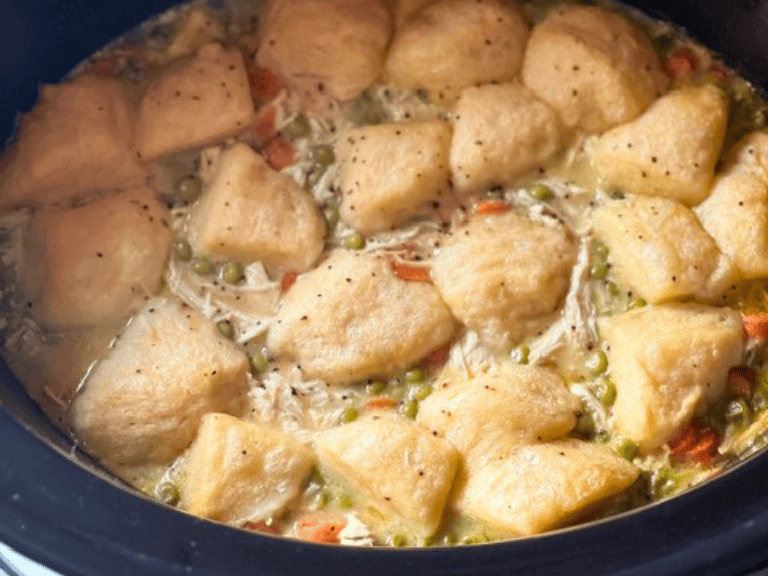 Cooked biscuit dumplings on top of creamy slow cooker chicken and vegetables before adding garnish.
