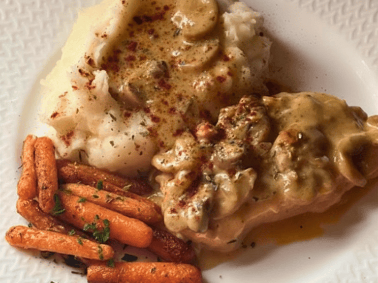 Slow cooker pork chops with mushroom gravy served over mashed potatoes with sautéed carrots on the side