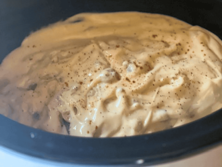 Pork chops cooking in mushroom gravy inside a slow cooker