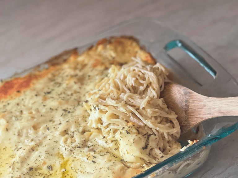 Creamy chicken tetrazzini casserole made with spaghetti, shredded chicken, and melted mozzarella cheese with a serving spoon scooping a portion from the baking dish.