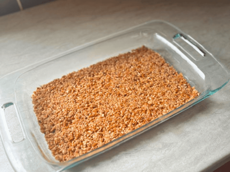 Buttery pretzel crust pressed firmly into a glass casserole dish, ready for the creamy cheesecake layer in Strawberry Pretzel Salad.