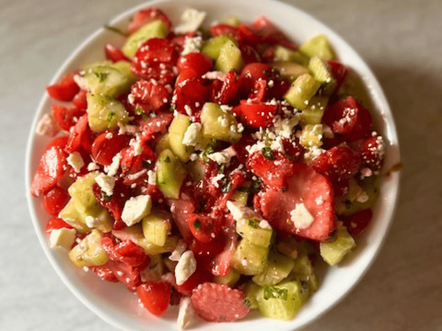 Strawberry cucumber salad with feta and fresh mint in a white bowl on a kitchen counter