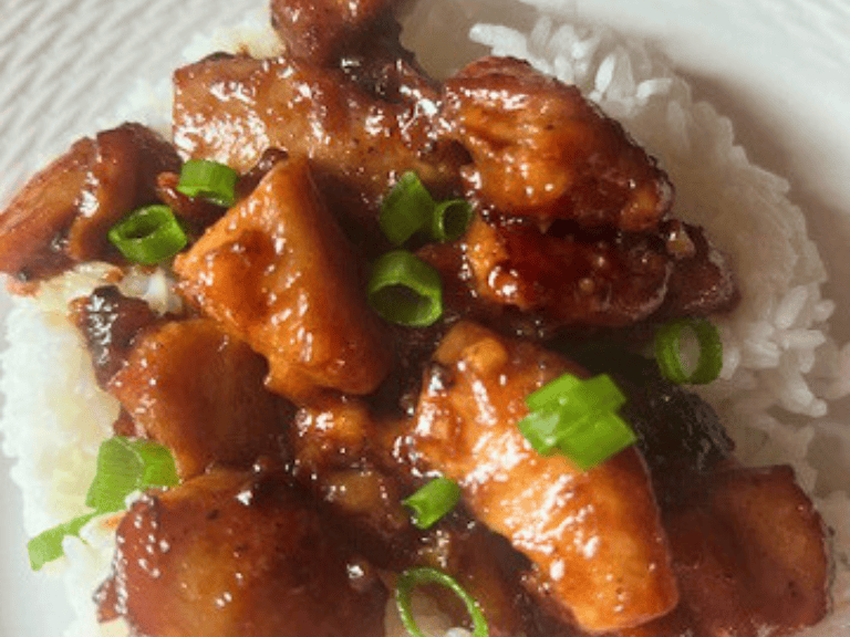 Whiskey sticky chicken served over white rice and topped with sliced green onions