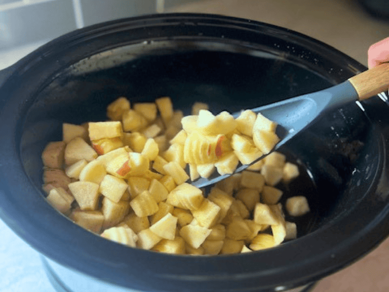 Cubed fresh apples in a slow cooker before cooking homemade applesauce.