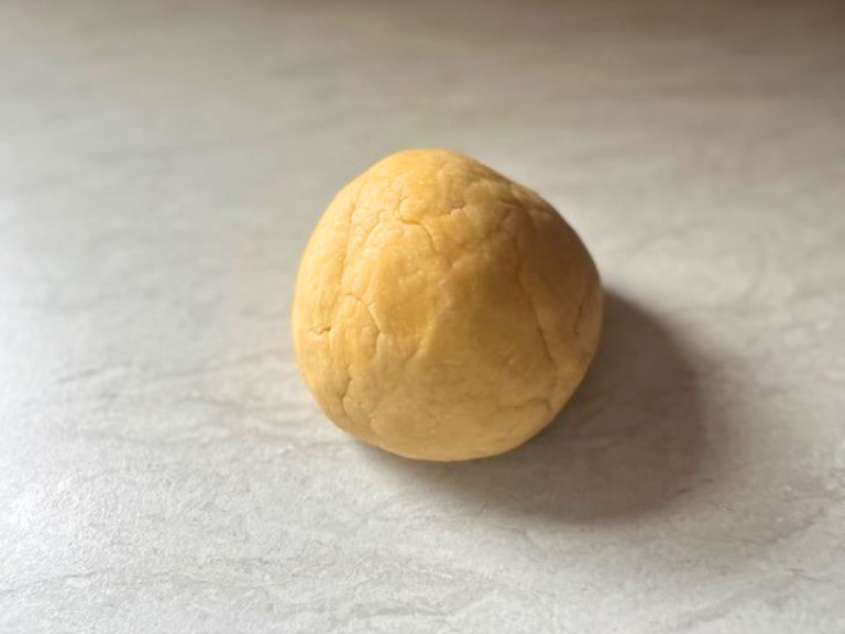 Smooth ball of homemade fettuccine dough after kneading.